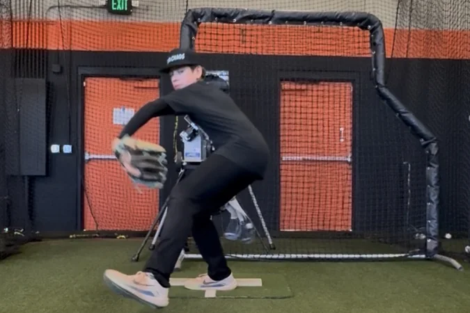 A young pitcher mid-delivery, focused on his own mechanics